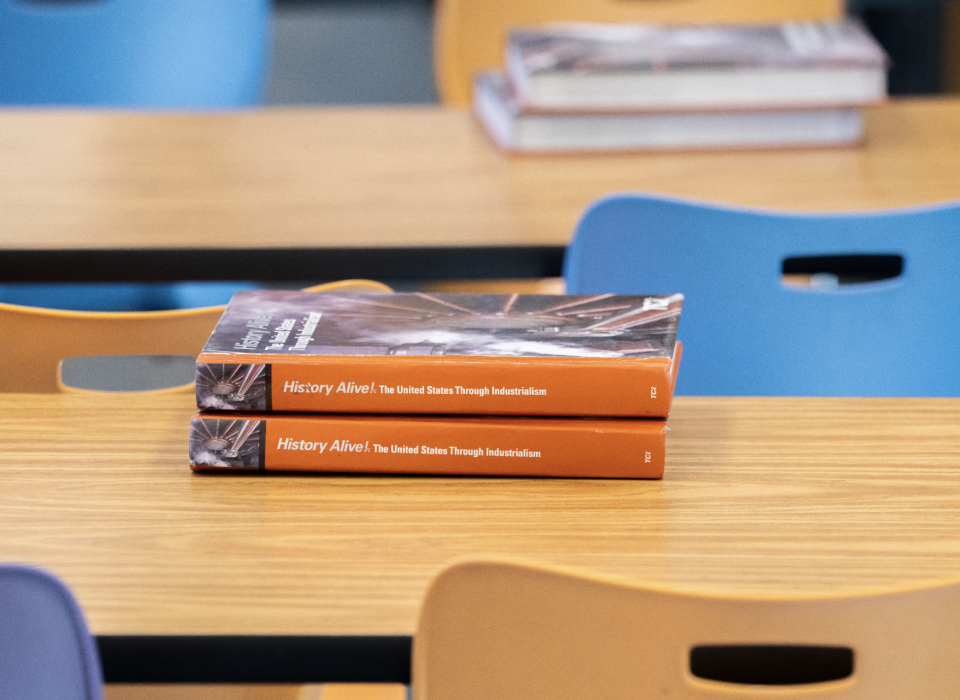 A close up of an empty classroom table with two textbooks stacked on top.
