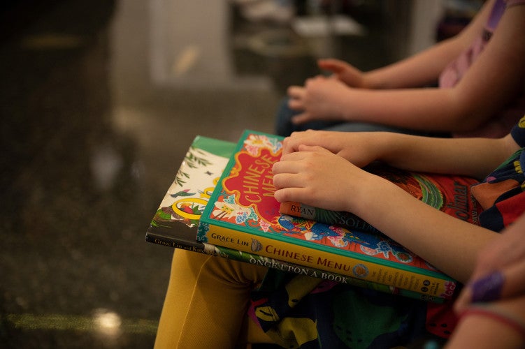 Two children's books sit in a young student's lap.