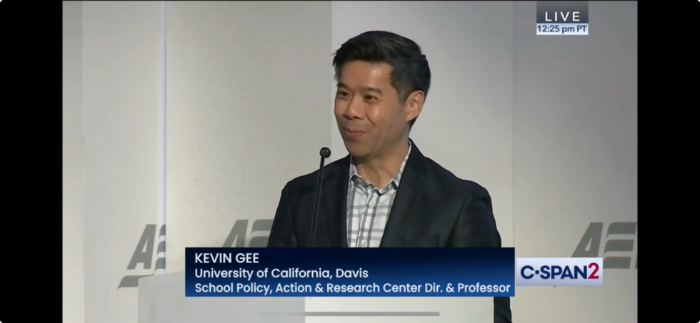 A video screenshot of Kevin Gee standing at a podium.