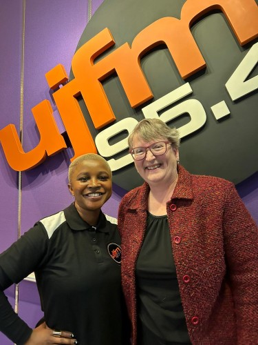 Lauren and radio host Sindiswa Ndala stand in front of a UJFM sign