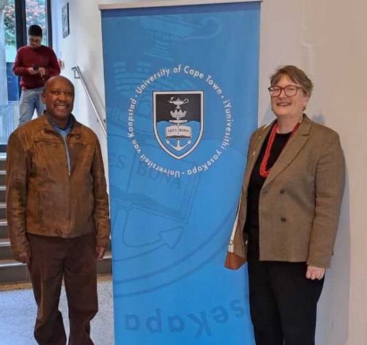 Lauren and Max standing next to a banner for the University of Cape Town. 