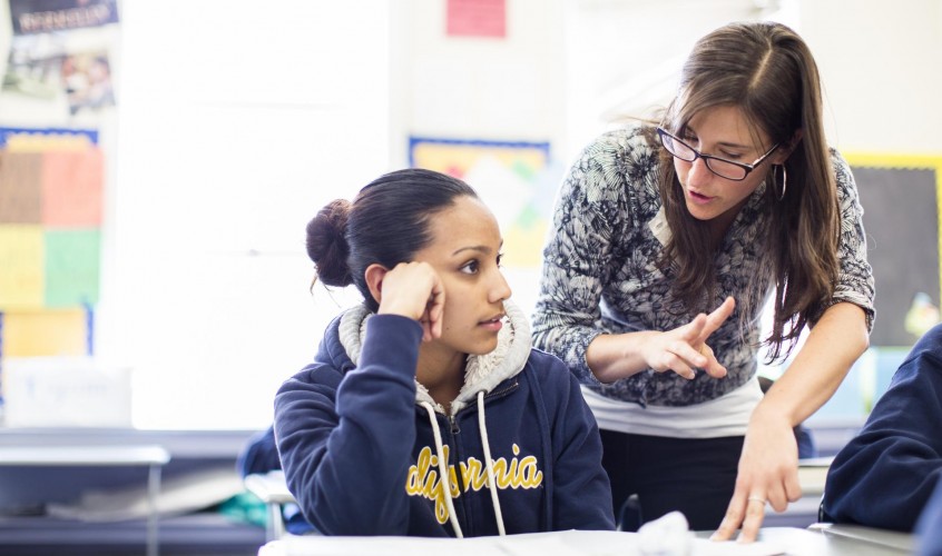 Teacher leans over to speak with student